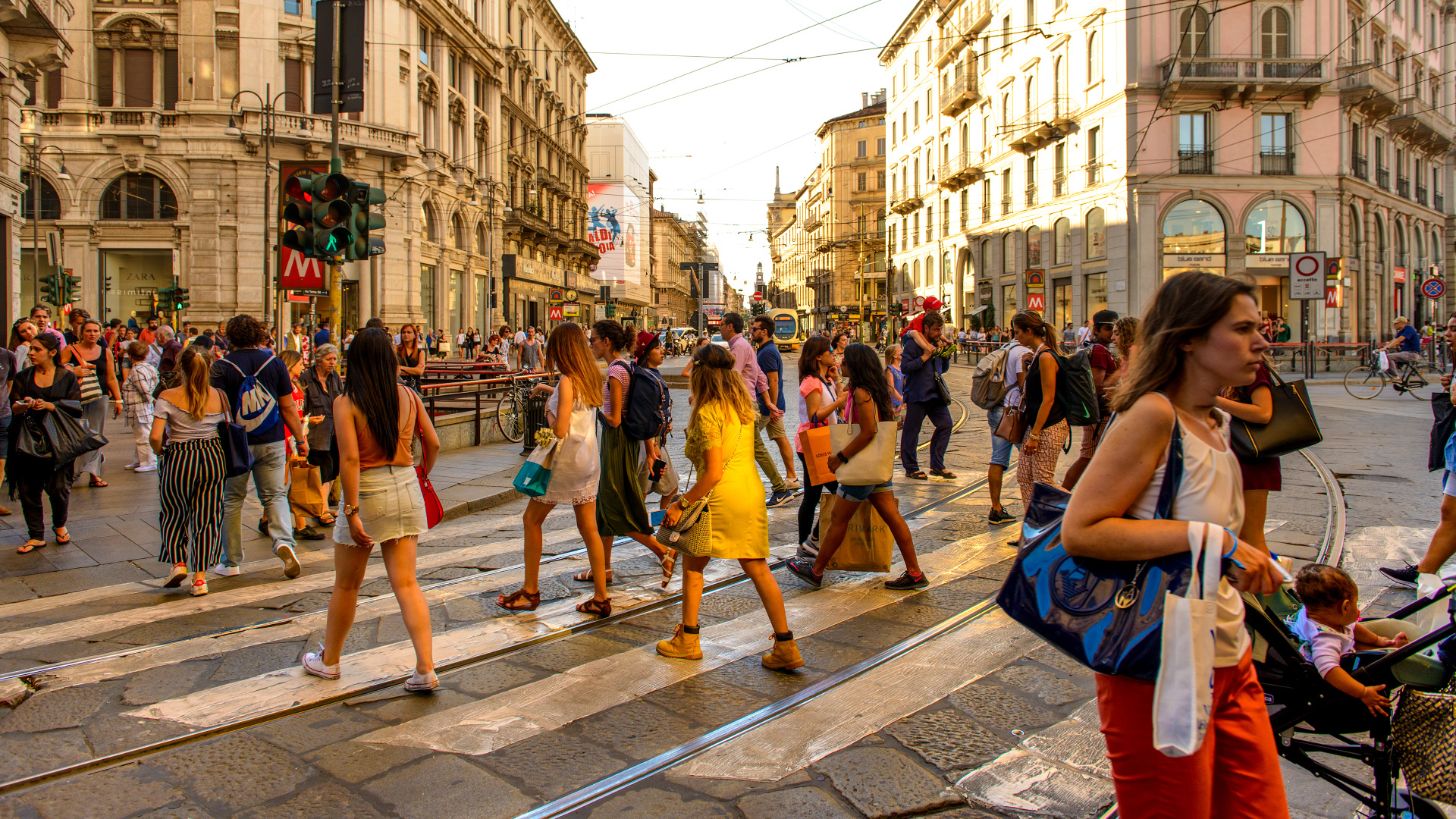Ritratti esposti e biciclette lungo una facciata: frammenti di storie nella città. Fotografia di Carlo Importuna.